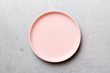 Çimento arka planındaki boş pembe tabağın üst görüntüsü. Tasarımın için boş boşluk.