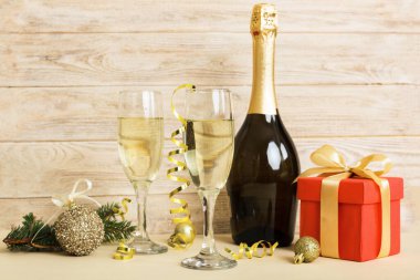 Champagne bottle with confetti, glasses and christmas decor on colored holiday background. Flat lay New Year decorations.