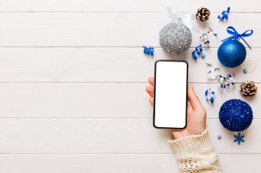 Mesaj atmak için yeri olan bir Noel modeli. Noel reklamı, uygulama şablonu. Masa arkasında boş ekran olan el ele tutuşan telefon. Mutlu yıllar ve Xmas Flat.