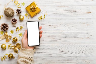 Mesaj atmak için yeri olan bir Noel modeli. Noel reklamı, uygulama şablonu. Masa arkasında boş ekran olan el ele tutuşan telefon. Mutlu yıllar ve Xmas Flat.