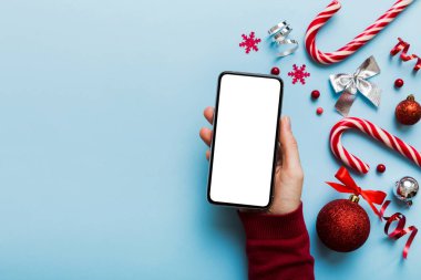 Mesaj atmak için yeri olan bir Noel modeli. Noel reklamı, uygulama şablonu. Masa arkasında boş ekran olan el ele tutuşan telefon. Mutlu yıllar ve Xmas Flat.