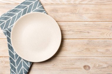 Renkli arka planda üst görünüm yiyecek için masa örtüsü üzerindeki boş yuvarlak beyaz tabak. Tasarımınız için boşluk olan peçeteye boş tabak.