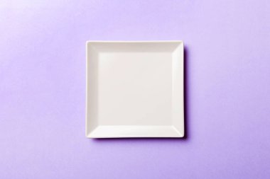Renkli arka plan görüntüsünün üst görüntüsü yiyecek için boş kare beyaz tabak. Tasarımınız için alanı olan boş tabak.