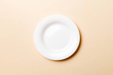 Renkli arka plan görüntüsünün üst görüntüsü yiyecek için boş yuvarlak beyaz tabak. Tasarımınız için alanı olan boş tabak.