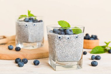 Sağlıklı kahvaltı ve chia tohumlu vanilyalı puding ve böğürtlenli masa arkası, vejetaryen gıda, diyet ve sağlık konsepti. Hindistan cevizi sütü ve yabanmersinli Chia pudingi..