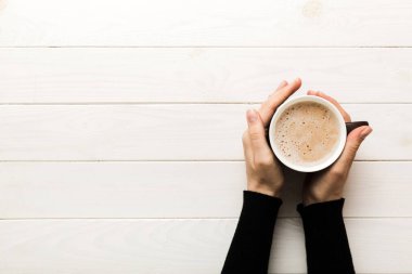 Renkli arka planda bir fincan kahve tutan minimalist stil bir kadın. Düz yerde, kapuçino bardağının üstünde. Metin için boş yer, kopyalama alanı. Kahve bağımlılığı. Üst manzara, düz uzanma.