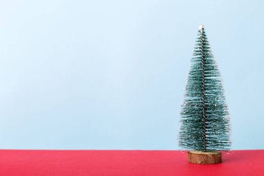 One small Christmas tree on colored background. new year decoration with copy space.