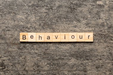 Ahşap bloğa yazılmış bir kelime. Beton masadaki davranış metni desing, konsept için.