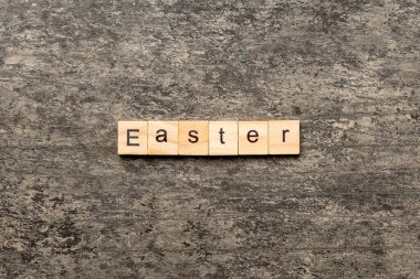 Tahta blokta yazan Paskalya kelimesi. Paskalya metni çimento masasında desing, konsept için.