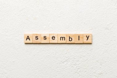 Tahta bloğa yazılmış bir kelime. Çimento sehpasında senin desing, konsept için ASSEMBLY metin.