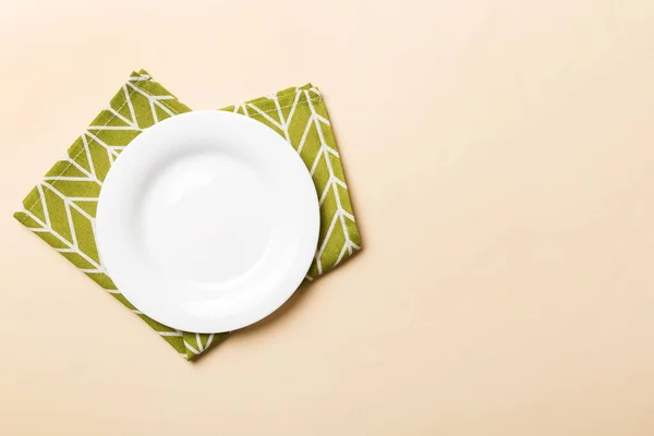 食べ物のためのテーブルクロス上の色の背景の空の丸い白いプレートの上のビュー あなたのデザインのためのスペースとナプキンに空の料理 — ストック写真