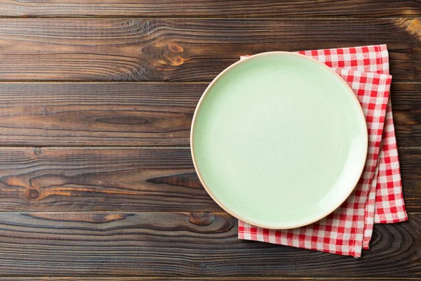 Top view on colored background empty round green plate on tablecloth for food. Empty dish on napkin with space for your design.
