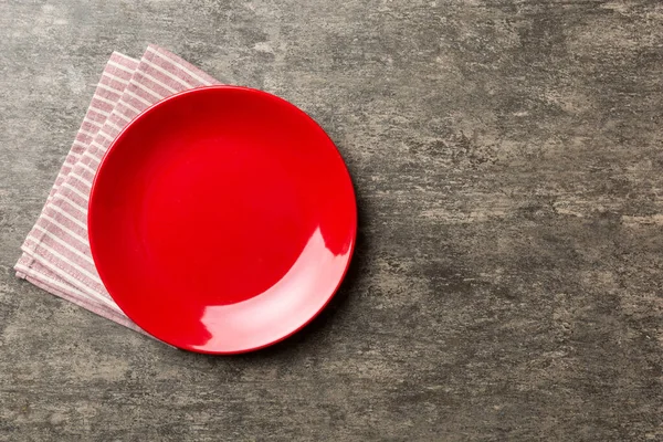 stock image Top view on colored background empty round red plate on tablecloth for food. Empty dish on napkin with space for your design.