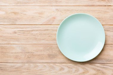 Ahşap zemindeki boş mavi tabağın üst görüntüsü. Tasarımın için boş boşluk.