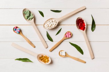 Renkli arka planda tahta kaşıkta vitamin ve mineral haplarının üst görünümü. Muhtelif ilaç haplarının en üst görüntüsü. Beslenme takviyesi sağlık ürünleri.