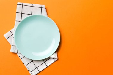 Renkli arkaplanda üst görünüm yiyecek için mavi tabak üzerinde boş. Tasarımınız için boşluk olan peçeteye boş tabak.