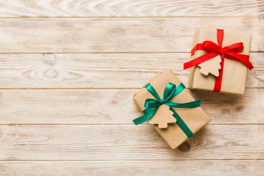 wrapped christmas or other holiday handmade present in paper with colored ribbon. Present box, decoration of gift on colourfull table, top view with copy space.