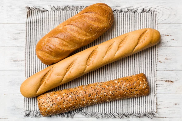 素朴なテーブルビューにナプキンと焼きたてのパンの盛り合わせ 無病息災のパン フランスパン — ストック写真