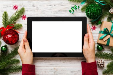 Evden Noel alışverişi, kadın elleri boş beyaz ekranlı tableti tutuyor. Kadın elinde tablet, boş ekran, Noel ağacı ve arka planda hediyeler..