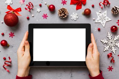Evden Noel alışverişi, kadın elleri boş beyaz ekranlı tableti tutuyor. Kadın elinde tablet, boş ekran, Noel ağacı ve arka planda hediyeler..