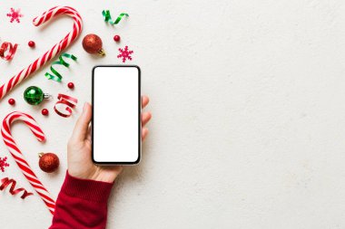 Mesaj atmak için yeri olan bir Noel modeli. Noel reklamı, uygulama şablonu. Masa arkasında boş ekran olan el ele tutuşan telefon. Mutlu yıllar ve Xmas Flat.