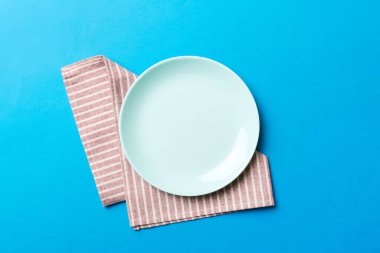 Renkli arkaplanda üst görünüm yiyecek için mavi tabak üzerinde boş. Tasarımınız için boşluk olan peçeteye boş tabak.