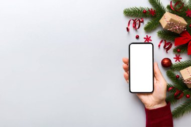 Digital phone mock up with rustic Christmas decorations for app presentation top view with empty space for you design. Christmas online shopping concept. Tablet with copy space on colored background.