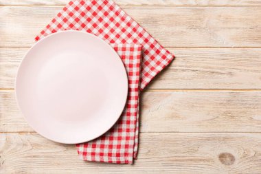 Renkli arka planda üst manzara. Yemek için masa örtüsü üzerine yuvarlak pembe tabak. Tasarımınız için boşluk olan peçeteye boş tabak.