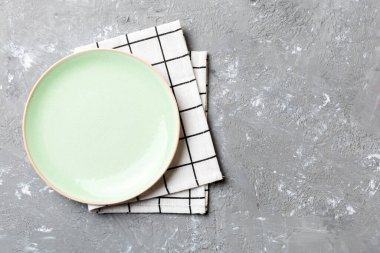 Renkli arka planda üst görünüm yiyecek için masa örtüsünün üzerinde boş yuvarlak yeşil tabak. Tasarımınız için boşluk olan peçeteye boş tabak.