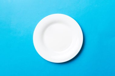 Renkli arka plan görüntüsünün üst görüntüsü yiyecek için boş yuvarlak beyaz tabak. Tasarımınız için alanı olan boş tabak.