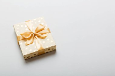 Noel 'i ya da diğer tatil hediyelerini renkli arka planda altın kurdeleli beyaz kağıda sardım. Şimdiki kutu, renkli tabloda hediye süslemesi, kopya alanı ile üst görünüm.