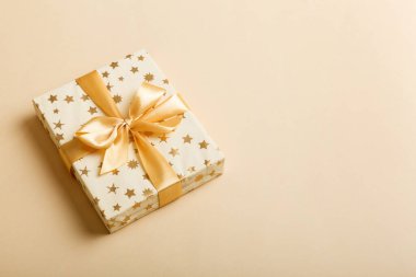 Noel 'i ya da diğer tatil hediyelerini renkli arka planda altın kurdeleli beyaz kağıda sardım. Şimdiki kutu, renkli tabloda hediye süslemesi, kopya alanı ile üst görünüm.