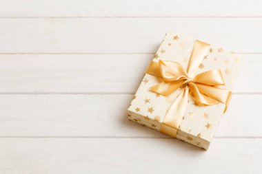 Noel 'i ya da diğer tatil hediyelerini renkli arka planda altın kurdeleli beyaz kağıda sardım. Şimdiki kutu, renkli tabloda hediye süslemesi, kopya alanı ile üst görünüm.