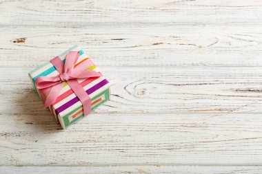 Noel 'i ya da diğer tatil hediyelerini renkli arka planda kurdeleyle renkli kağıda sardım. Şimdiki kutu, renkli tabloda hediye süslemesi, kopya alanı ile üst görünüm.