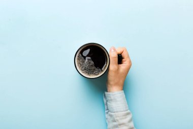 Renkli arka planda bir fincan kahve tutan minimalist stil bir kadın. Düz yerde, kapuçino bardağının üstünde. Metin için boş yer, kopyalama alanı. Kahve bağımlılığı. Üst manzara, düz uzanma.