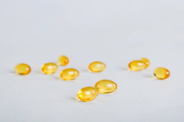 Heap of yellov pills on colored background. Tablets scattered on a table. Pile of red soft gelatin capsule. Vitamins and dietary supplements concept.
