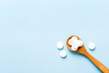 Renkli arka planda bir yığın beyaz hap. Tabletler masaya saçılmış. Kırmızı yumuşak jelatin kapsül yığını. Vitaminler ve beslenme takviyeleri konsepti.