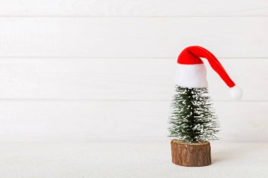 One small Christmas tree with santa hat on colored background. new year decoration with copy space.