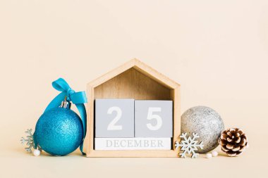 25 december. Christmas composition on colored background with a wooden calendar, with a gift box, toys, bauble copy space.