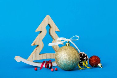 Christmas ball with decorative wooden tree on colored background. decoration bauble with ribbon bow with copy space.