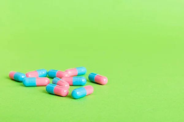 stock image Heap of pink and blue pills on colored background. Tablets scattered on a table. Pile of red soft gelatin capsule. Vitamins and dietary supplements concept.