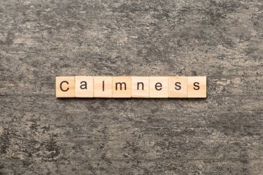 Tahta blokta sakinlik kelimesi yazılı. Çimento masasındaki sakinlik metni desing, konsept için.