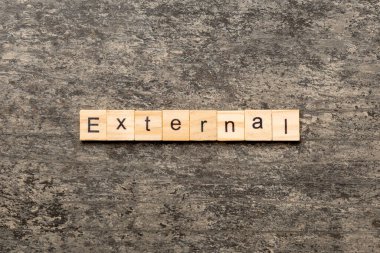 Tahta blokta EXTERNAL kelimesi yazıyor. Deksing, konsept için EXTERNAL metin çimento tablo üzerinde.