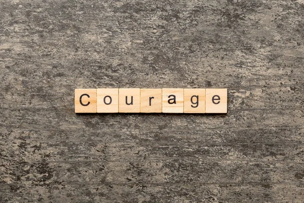 木のブロックに書かれた勇気の言葉 あなたのデザイン コンセプトのためのセメントテーブル上の勇気のテキスト — ストック写真