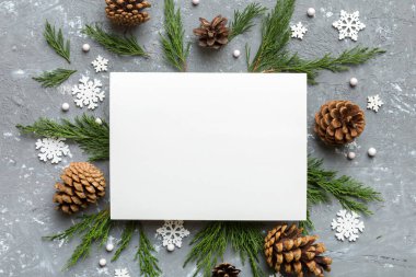 Noel kompozisyonu düzdü. Kare kağıt boş, çam ağacı dalları, renkli arka planda noel süslemeleri. Üst görünüm, metin için boşluk kopyala.