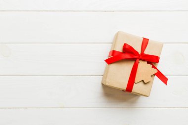 wrapped christmas or other holiday handmade present in paper with colored ribbon. Present box, decoration of gift on colourfull table, top view with copy space.