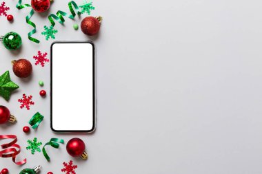 Noel alışverişi ev telefonundan, boş beyaz ekranlı üst manzaralı. Renkli arka planda fotokopi alanı ve Noel süsleme topları olan akıllı cep telefonu. Kış tatillerinde satış geçmişi.