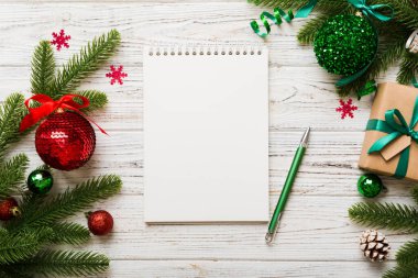 Noel 'i yazmak için bir kadın not defterine Xmas dekorasyonlu renkli arkaplan çiziyor.