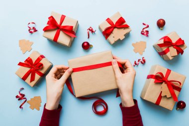 Kadınlar Noel tatili için sürpriz hediyeler hazırlıyor. İş yerinde el aletleri ve manzarayla oturuyor. Renkli masada Noel hediyesini paketleyen kadın..