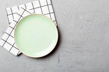 Renkli arka planda üst görünüm yiyecek için masa örtüsünün üzerinde boş yuvarlak yeşil tabak. Tasarımınız için boşluk olan peçeteye boş tabak.